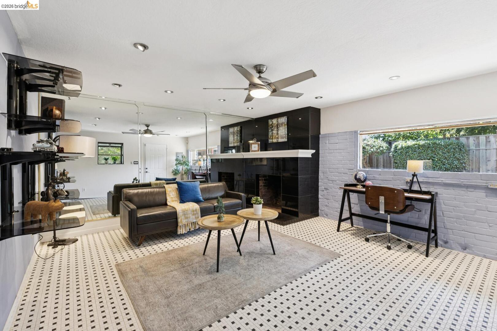 Living room with a dark fireplace, leather sofa, mirrored wall, and patterned tile floor.