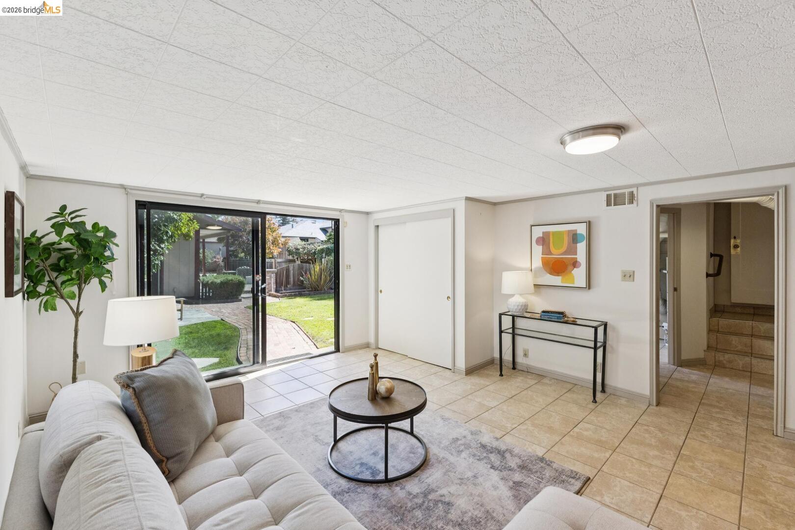 Furnished living room with sliding glass doors overlooking a backyard patio and lawn.