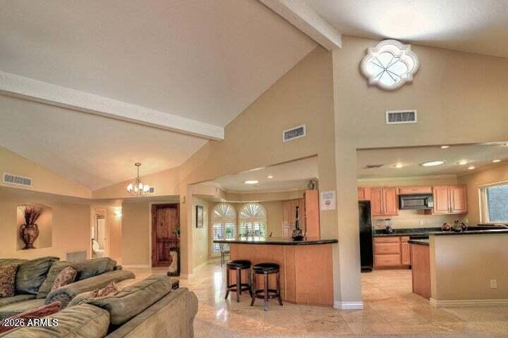 Open living room and kitchen with a vaulted ceiling, sectional sofa, and breakfast bar.