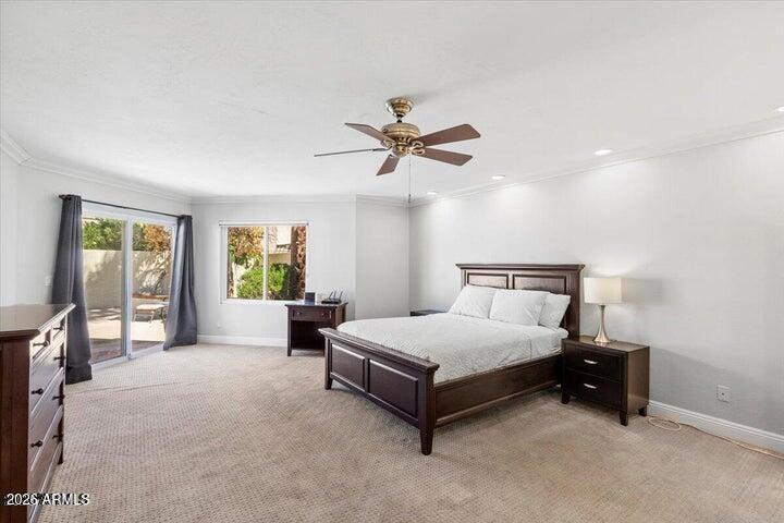 Bedroom with a dark wood bed, ceiling fan, and sliding glass doors opening toward a patio.
