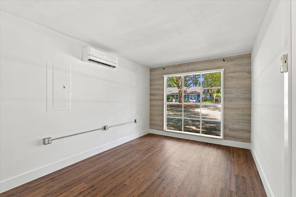 Empty room with wood-look flooring, a large window, and a wood-look accent wall.