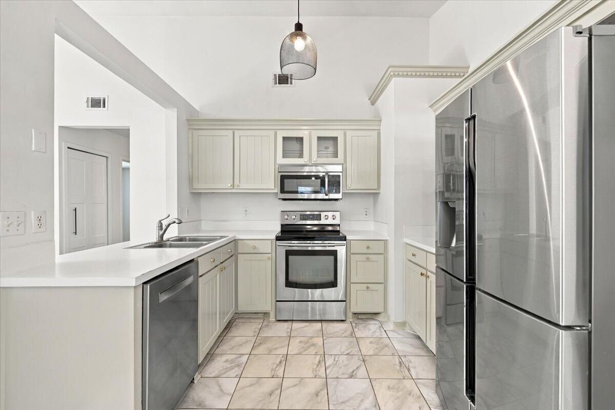 Kitchen with white cabinetry, stainless steel appliances, and marble-look tile flooring.