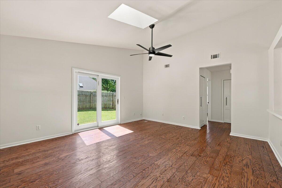 Empty room with hardwood floors, sliding glass doors, and a black ceiling fan.