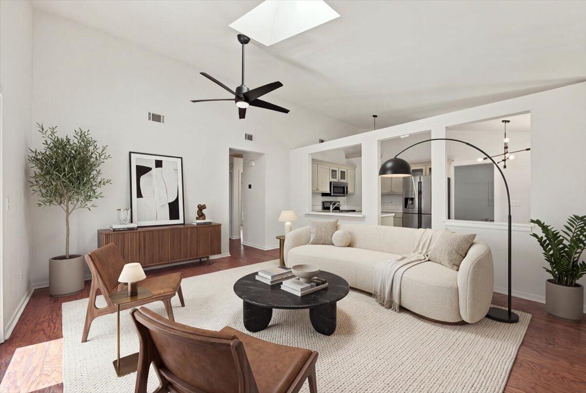 Living room with a vaulted ceiling, white sofa, and open kitchen.