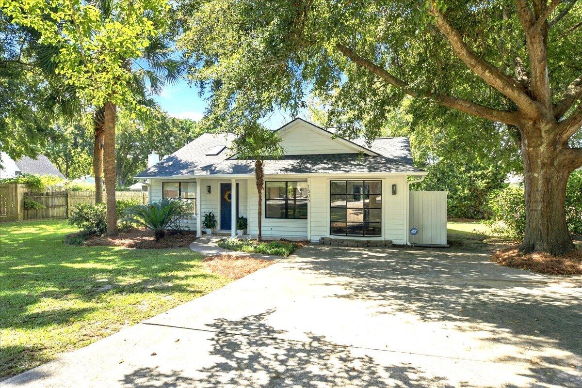 Single-story house with a blue front door and broad driveway beneath mature shade trees.