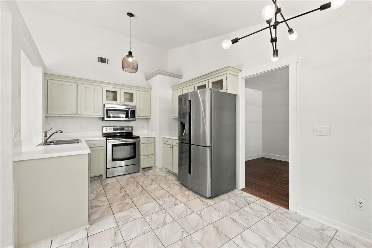 Kitchen with pale cabinets, stainless steel appliances, and marble-pattern tile flooring.