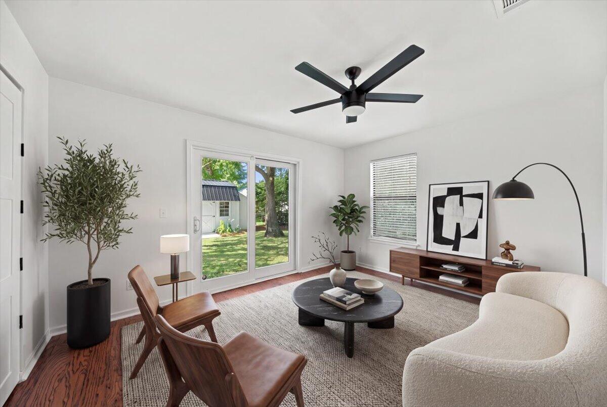 Staged living room with a curved cream sofa and sliding glass doors overlooking a green yard.
