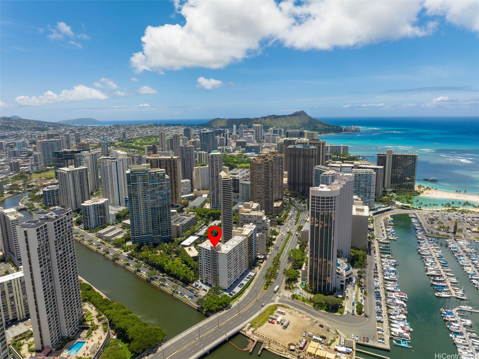 Aerial view of a marked Honolulu high-rise, with Diamond Head, the marina, and Ala Wai Canal beyond.