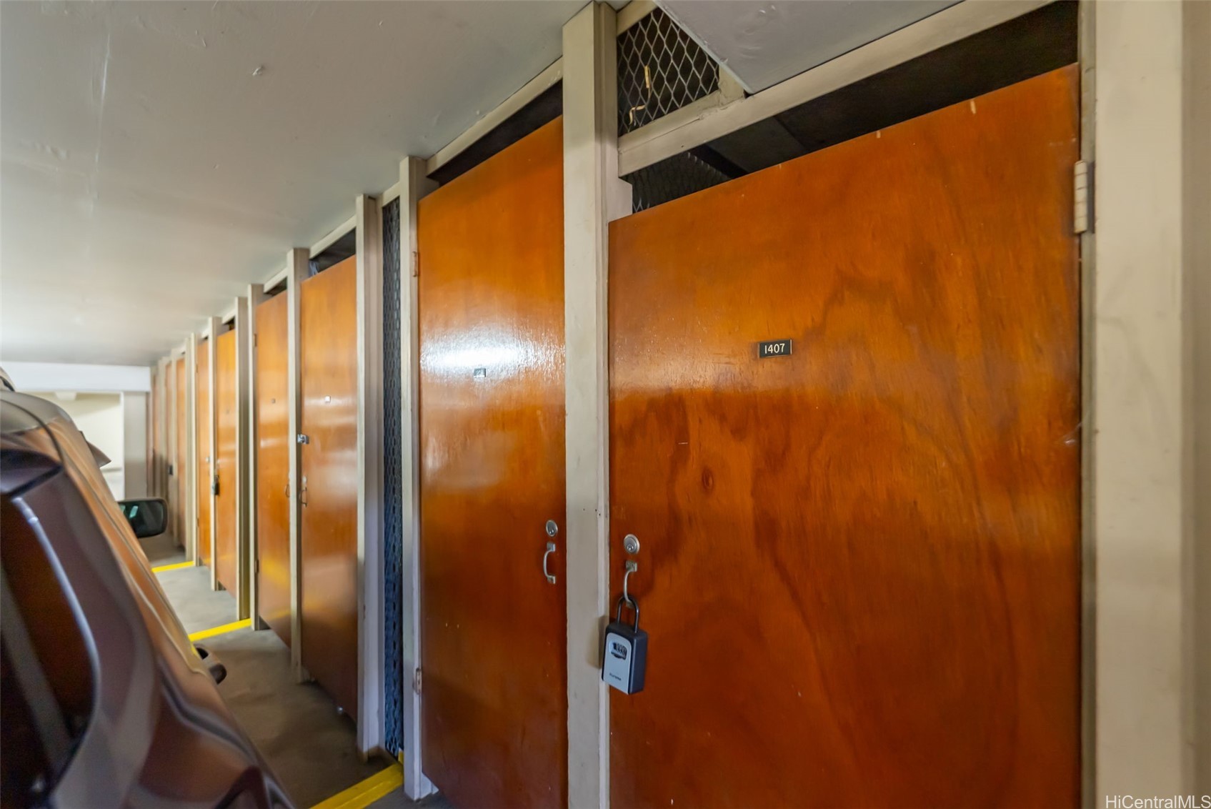 Wooden storage lockers line a corridor beside a parked vehicle; the nearest door is marked 1407.