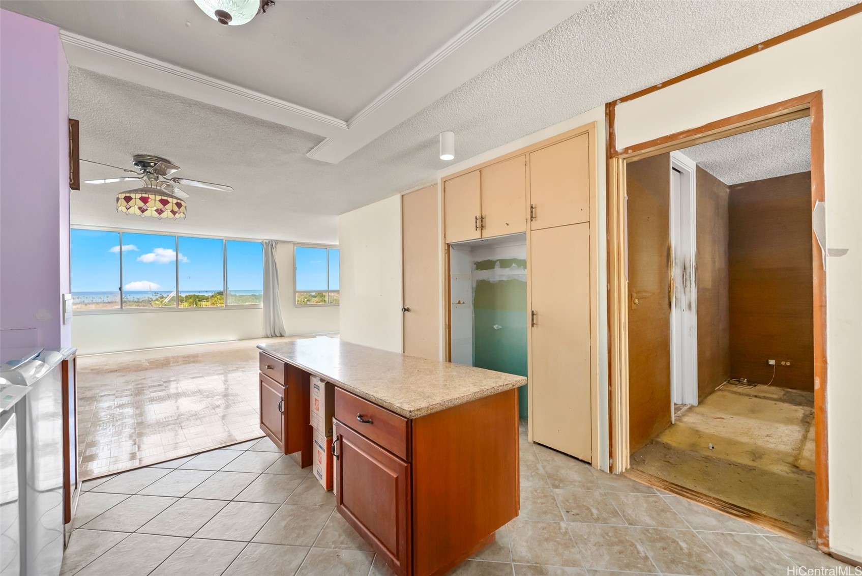 Vacant condo kitchen with a wood island and ocean views through large living-area windows.