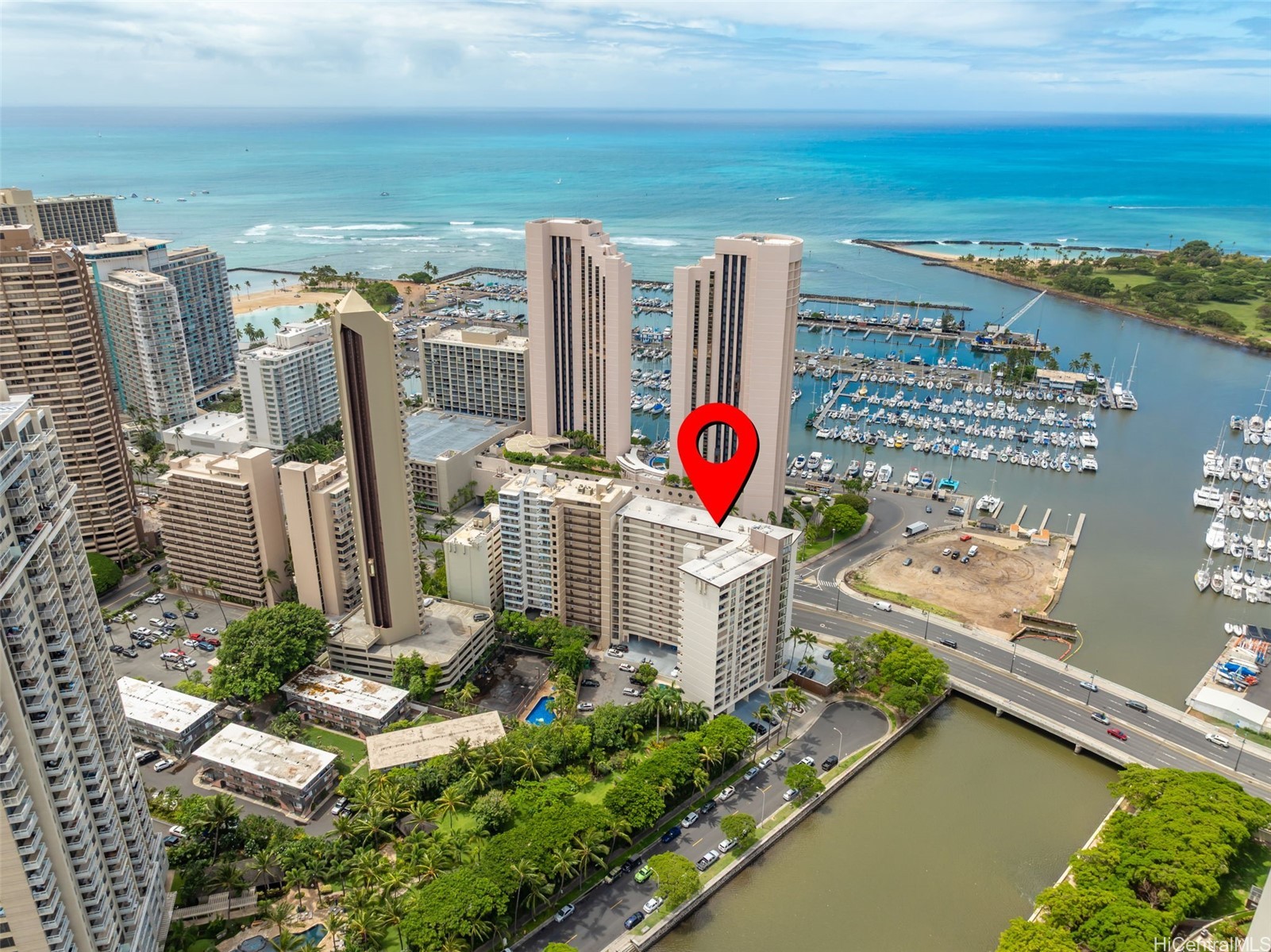 Honolulu high-rise marked beside a marina, with the ocean and harbor in the background.