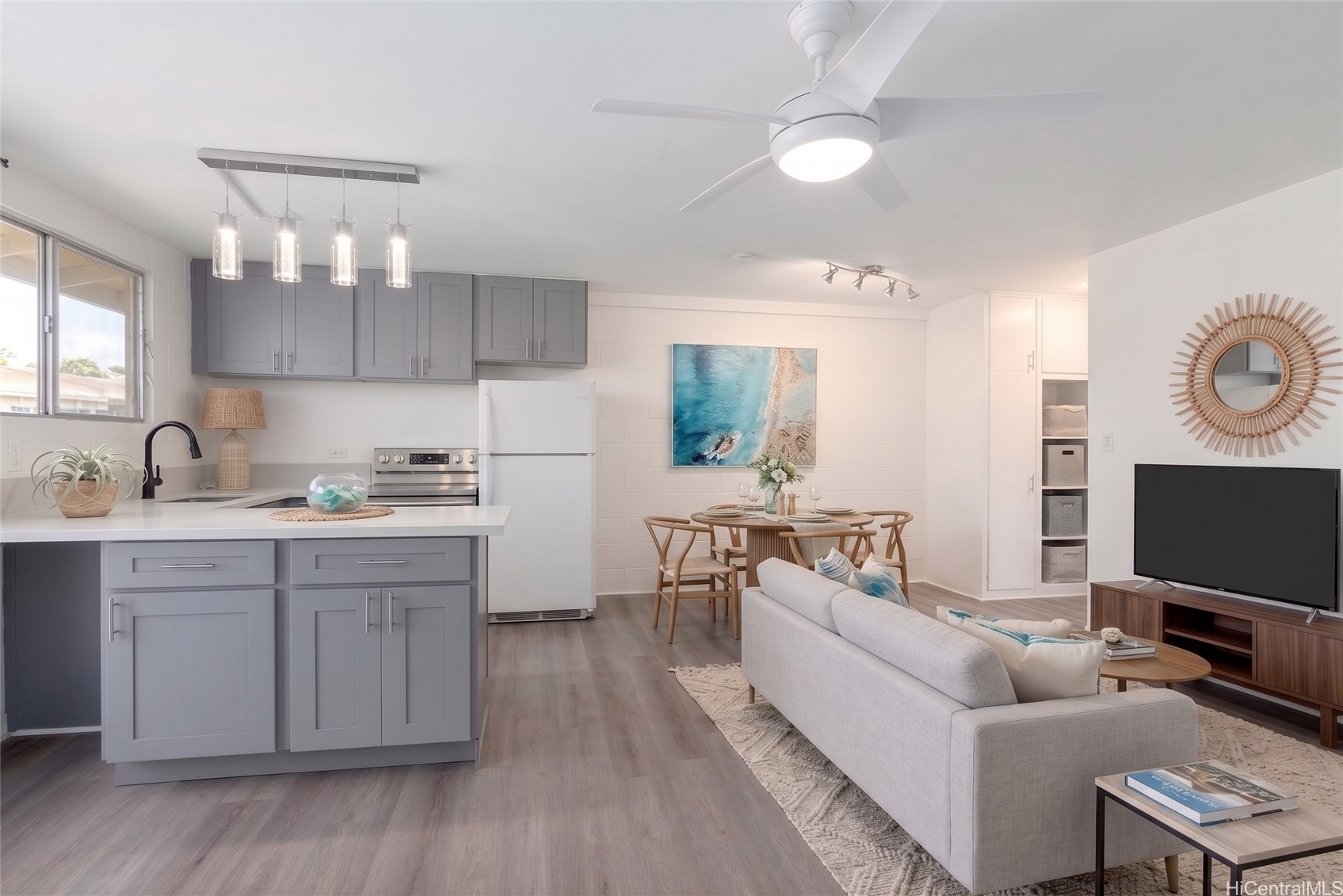 Open-plan kitchen and living room with gray cabinets, a dining area, and a white sofa.