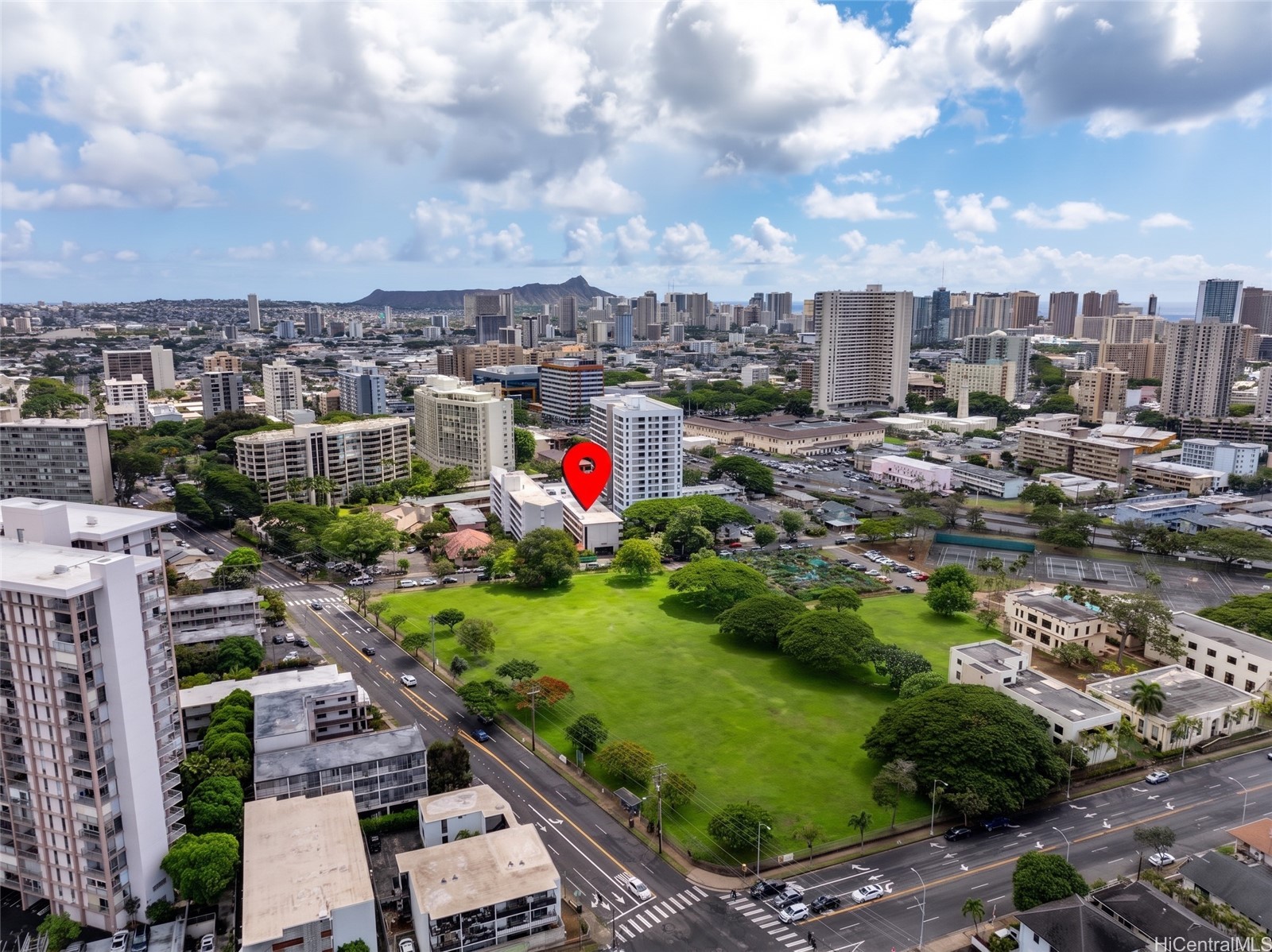 Aerial view of the property marked among Honolulu high-rises, with a green field and mountains beyond.