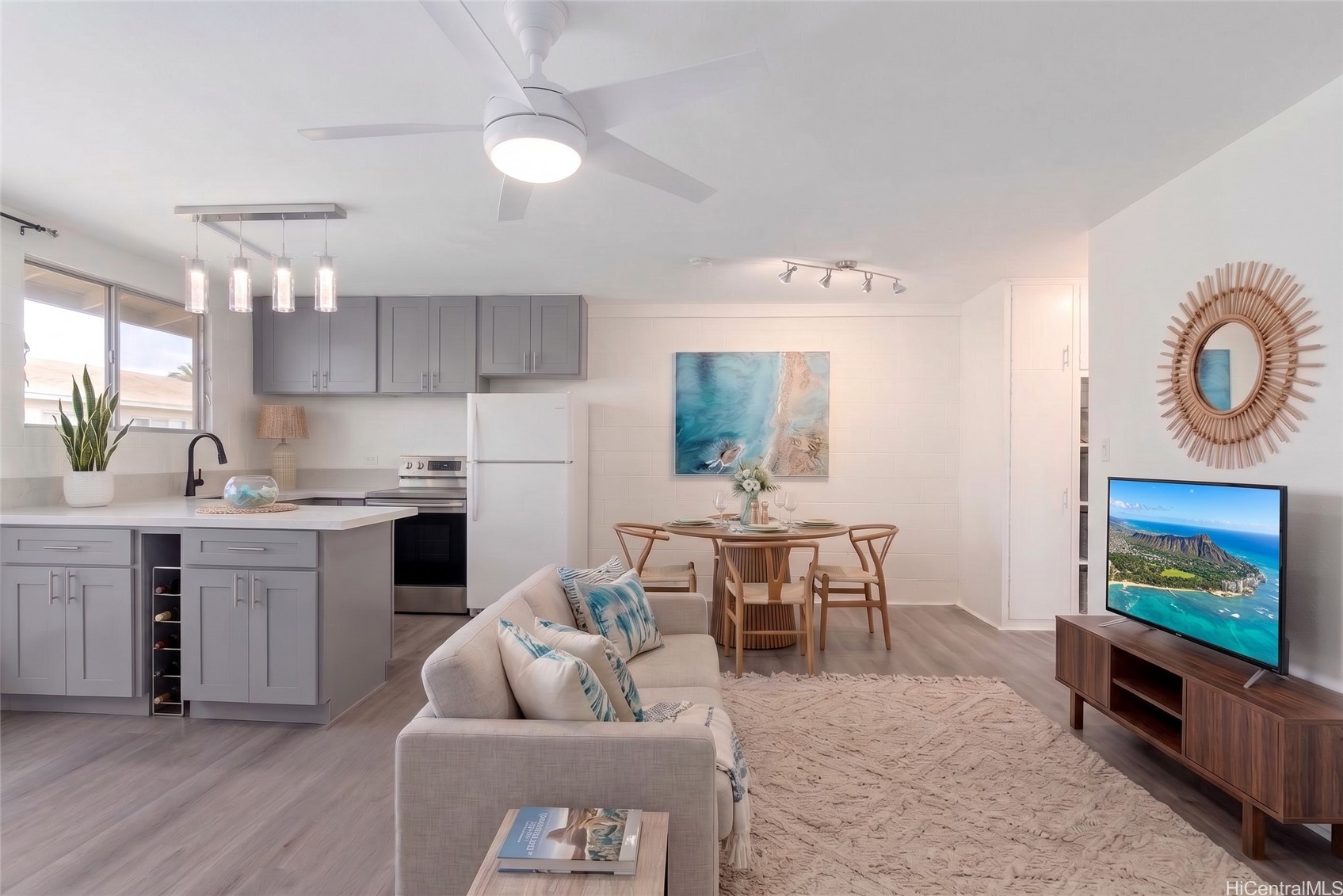 Open-plan living room and kitchen with gray cabinets, a dining table, and a light sofa with blue accents.