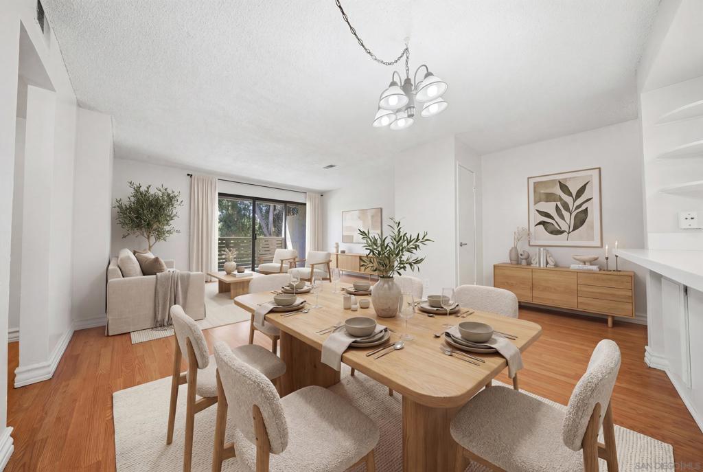 Dining room with a set wooden table, upholstered chairs, and sliding glass doors beside the living area.