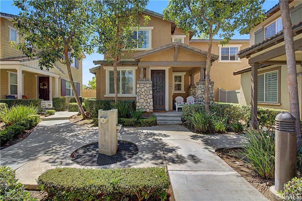 Tan two-story home with stone porch columns and a landscaped courtyard fountain.