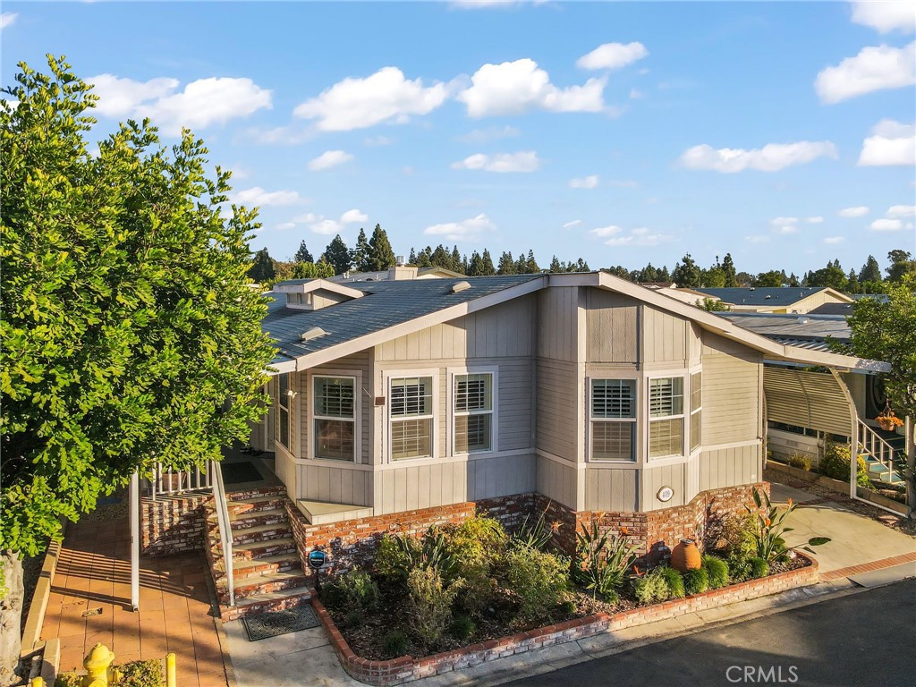 Single-story gray home with brick lower walls, landscaped garden, and front steps.