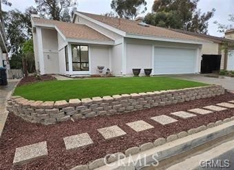 Single-story home with a two-car garage, curved stone retaining wall, and stepping-stone path.