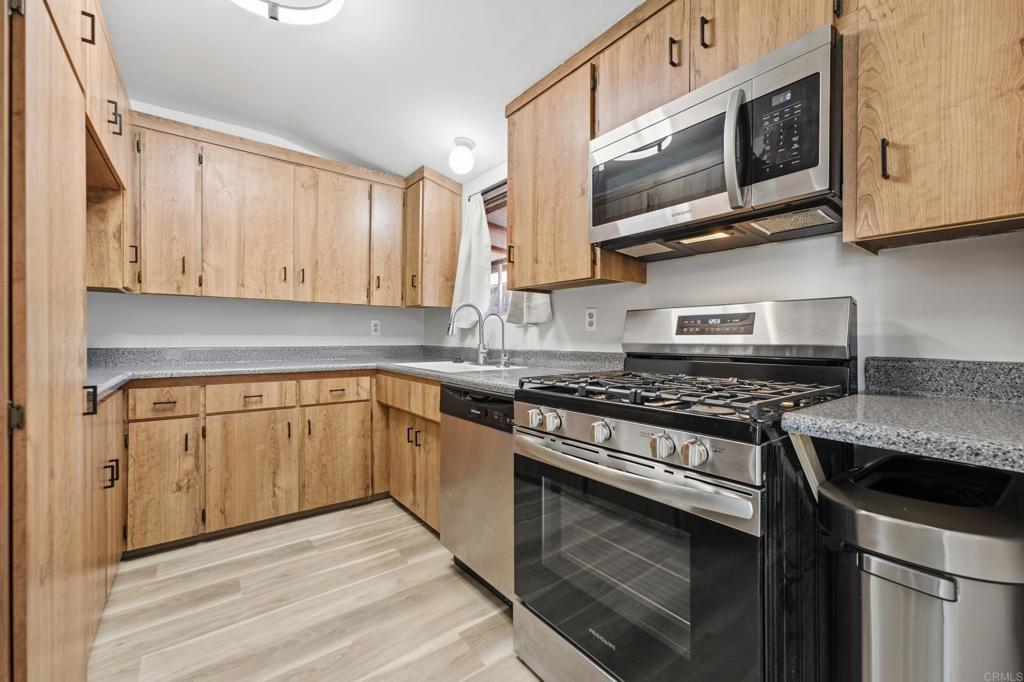 Kitchen with light wood cabinets, granite counters, and stainless steel appliances.