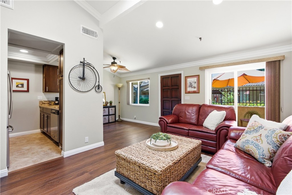 Furnished living room with red leather sofas and sliding doors overlooking a patio with an orange umbrella.