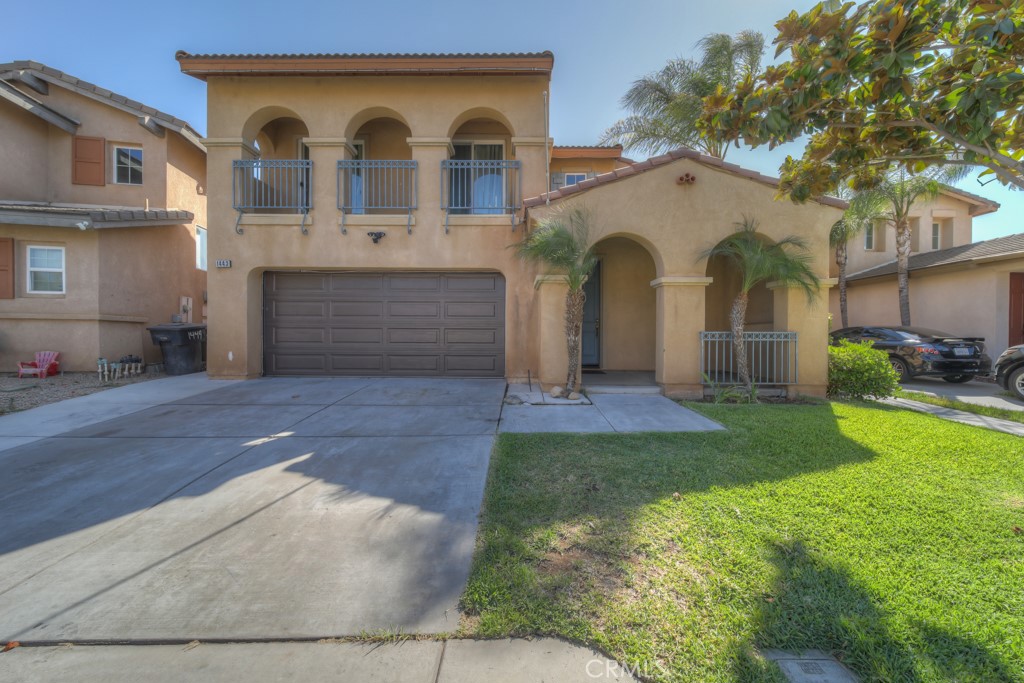 Two-story tan stucco home with arched balconies, a double garage, and a broad driveway.