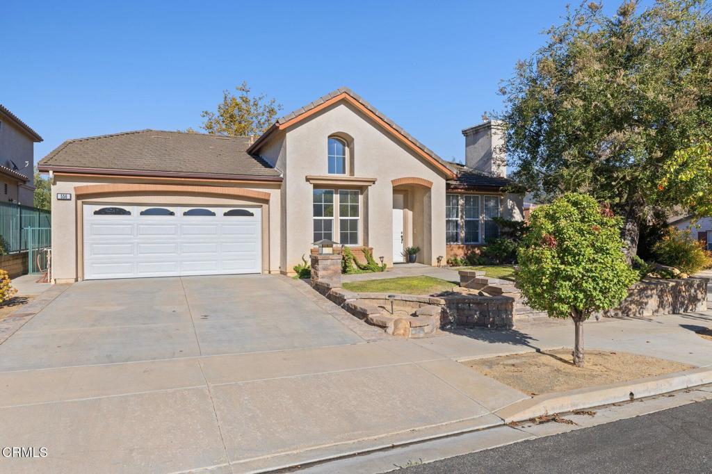 Stucco home with a two-car garage, wide driveway, and landscaped front yard.