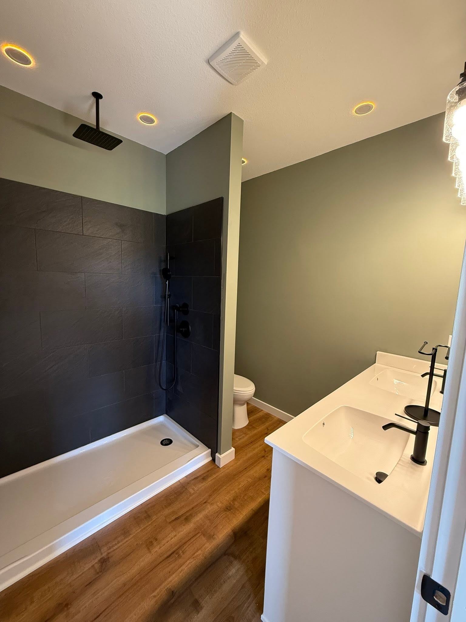Modern bathroom with a dark tiled walk-in shower and white double-sink vanity.