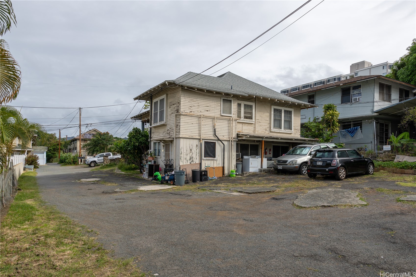 Weathered two-story wood building beside a paved parking area with parked cars.