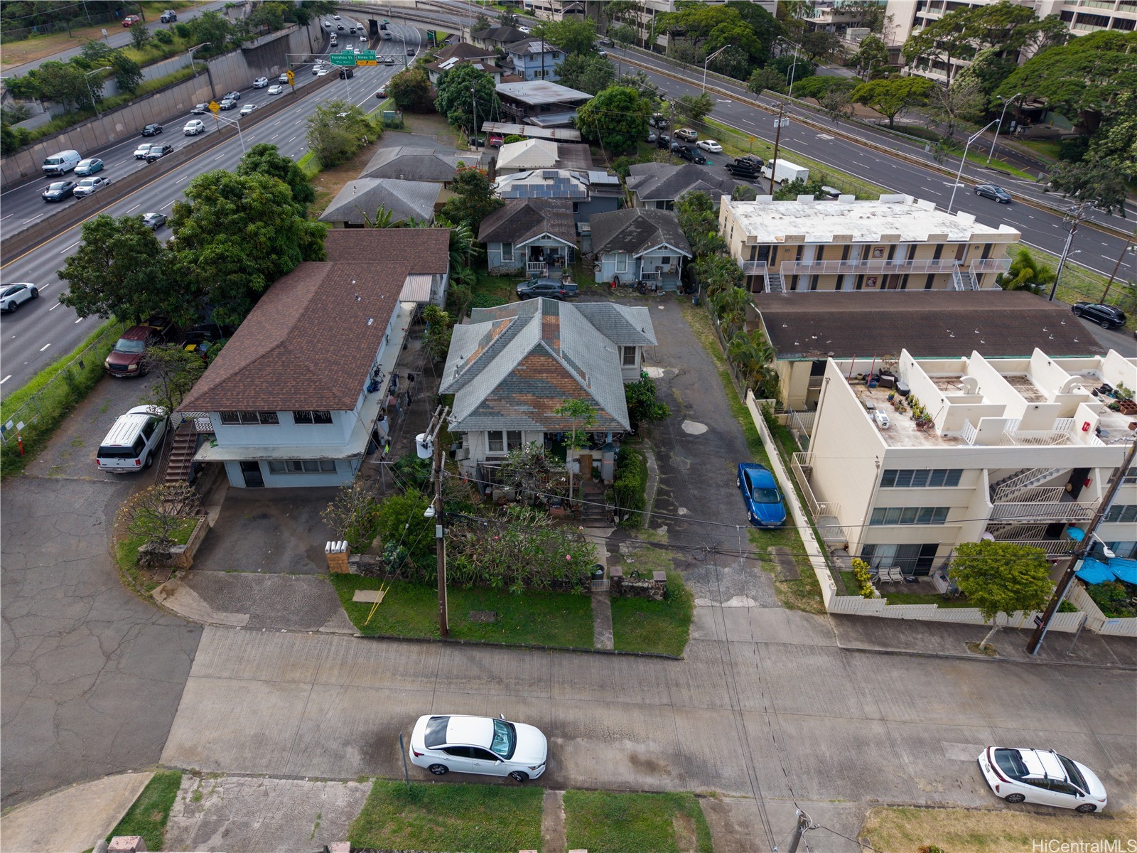 Aerial view of Honolulu homes and apartments beside a divided highway.