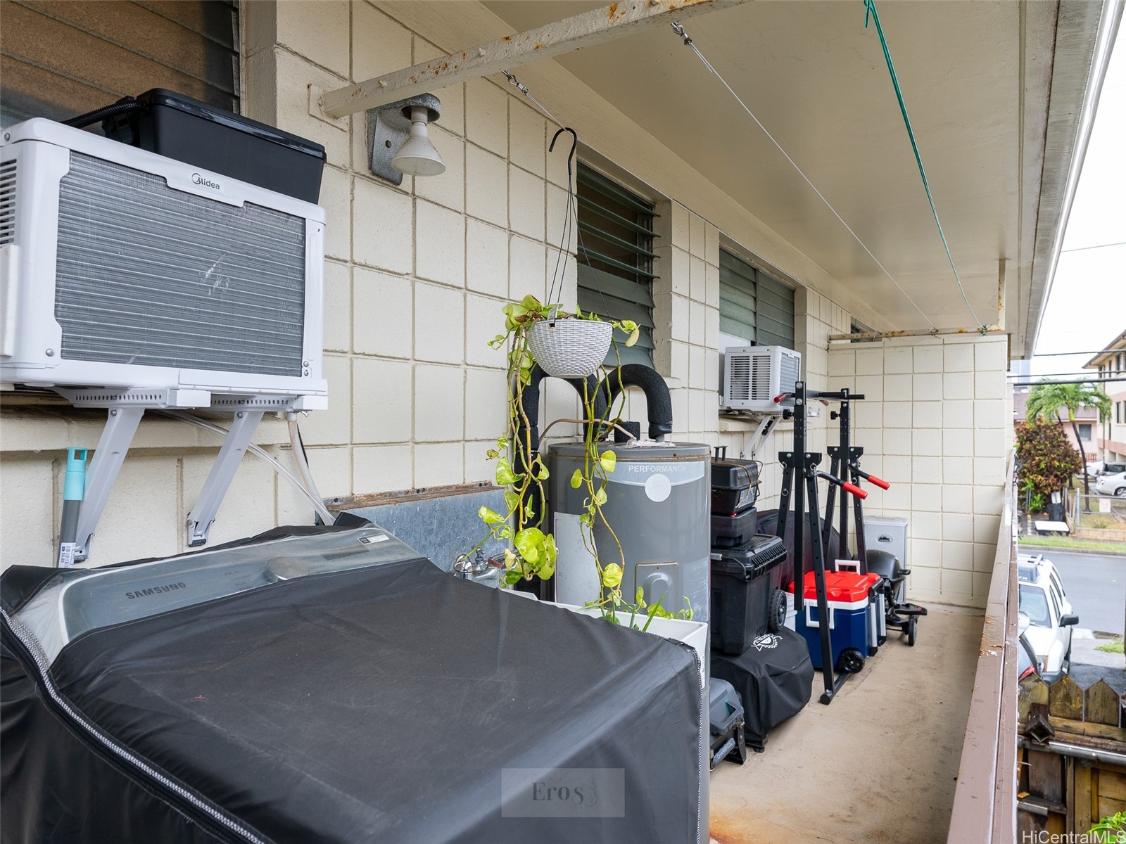 Covered exterior walkway lined with air-conditioning units and storage equipment.