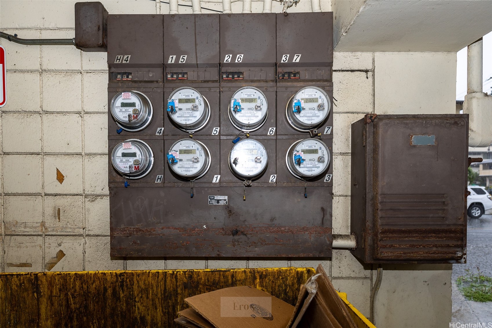 Electrical meters on a weathered wall beside a rusted utility cabinet.