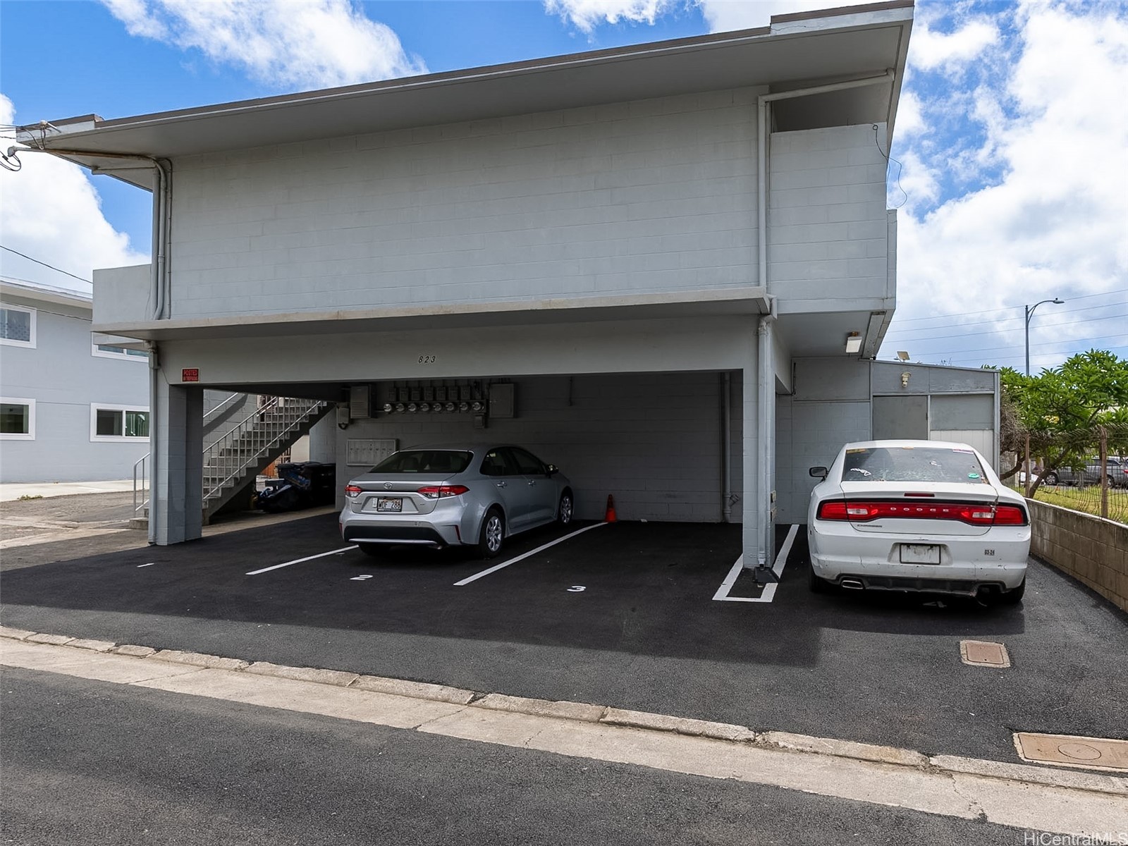 Two-story building with covered parking, two cars, and an exterior staircase.