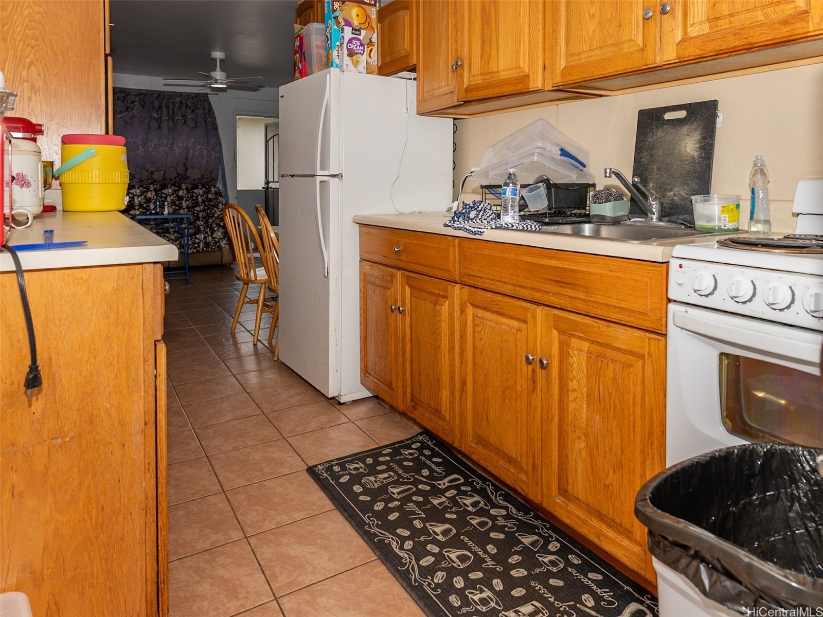 Kitchen with honey-colored wood cabinets, white appliances, and a tiled floor.