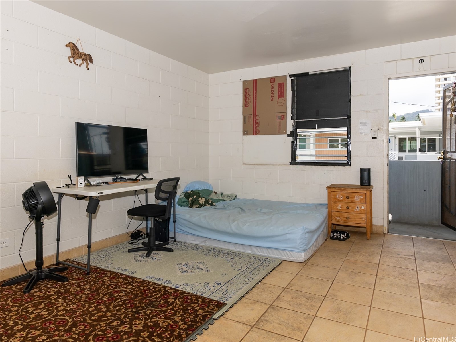 Bedroom with a bed, desk, television, and tiled floor