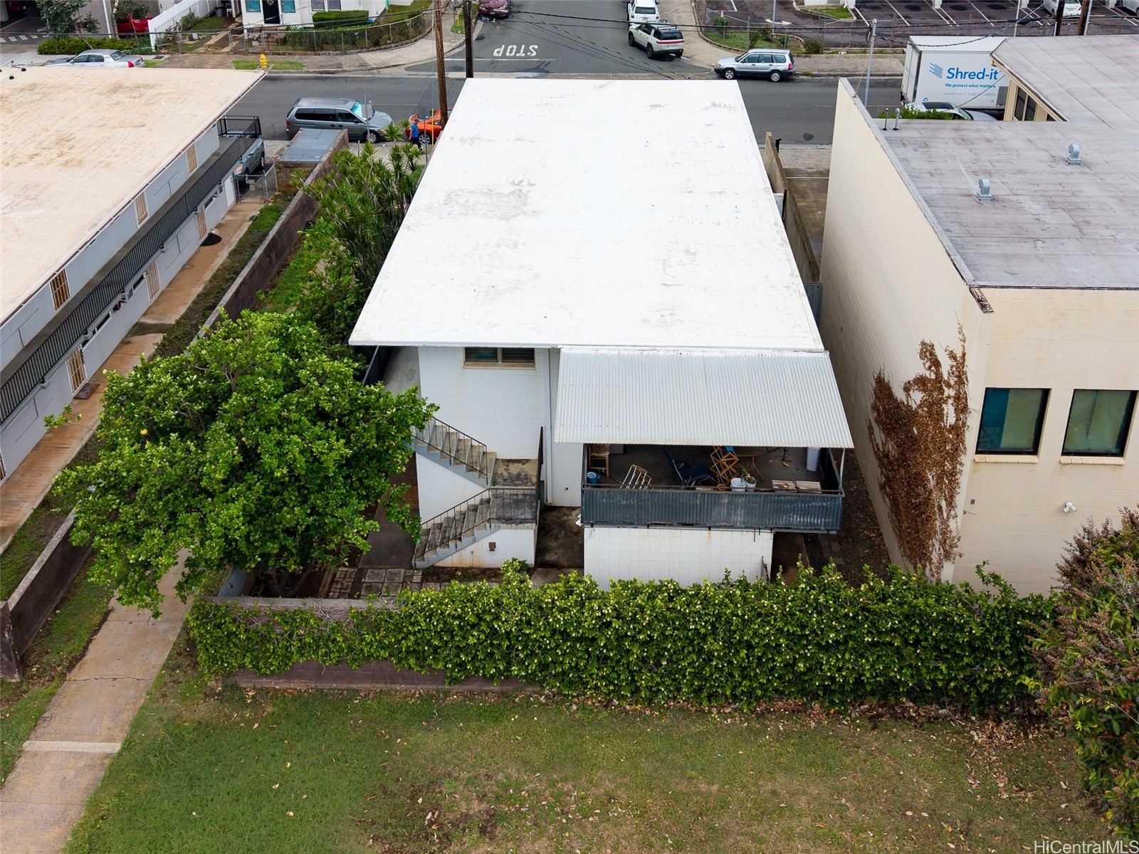 Aerial view of a low-rise commercial building with a broad white roof and exterior stairs.