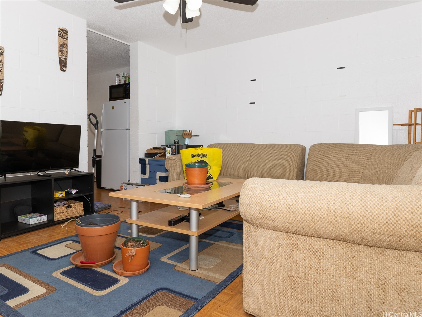 Living room with beige sectional, blue patterned rug, coffee table, and television.