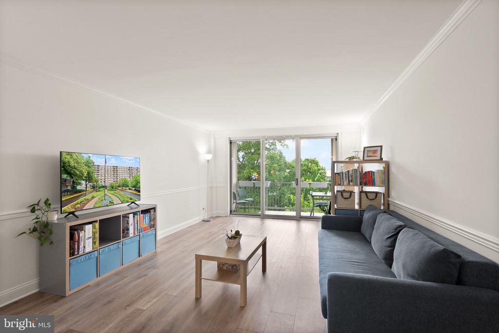 Living room with a blue-gray sectional and sliding doors to a leafy balcony.