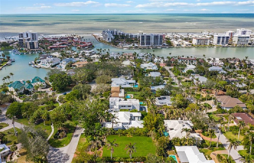 Aerial view of a Naples home and surrounding neighborhood, with waterways and the Gulf of Mexico beyond.