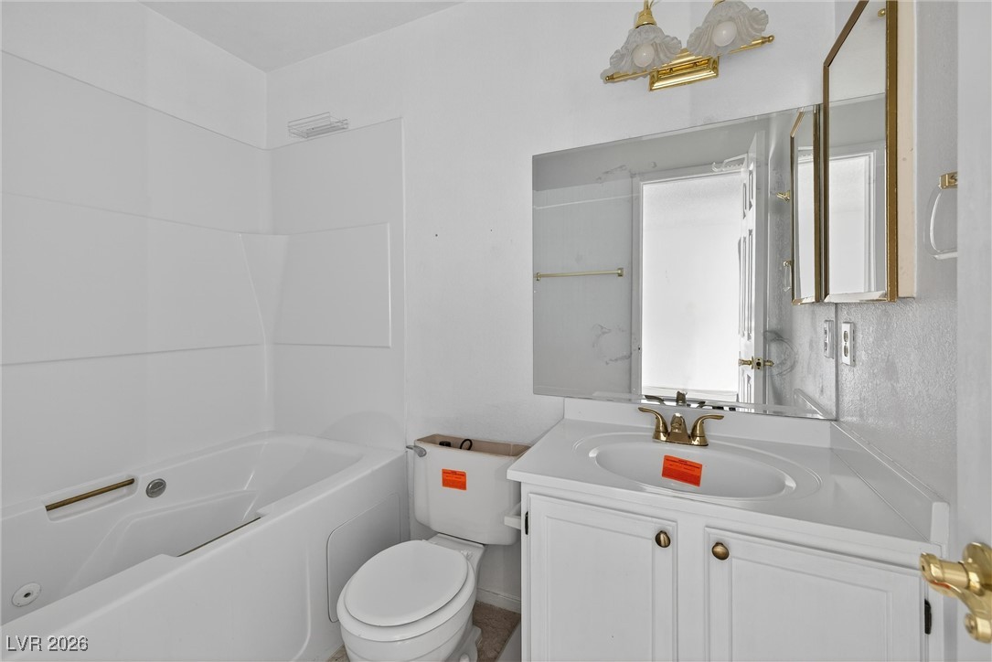 Bathroom with a white tub, toilet, and vanity with a mirrored cabinet.