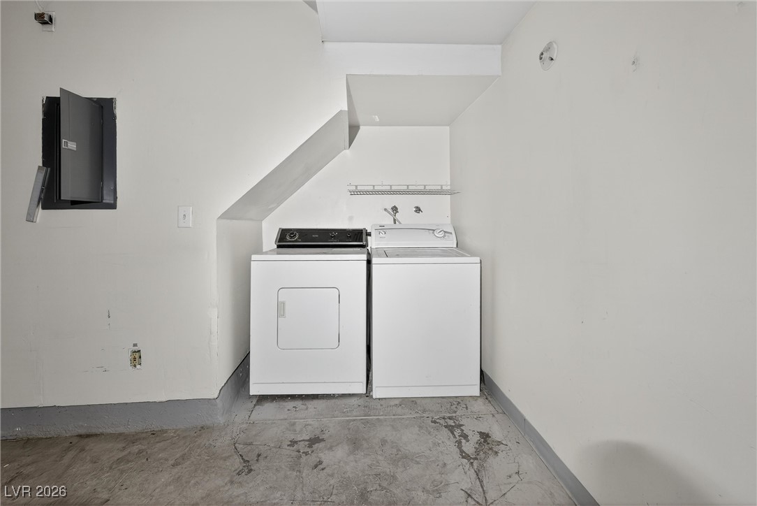 Laundry area with a white washer and dryer beneath a staircase.