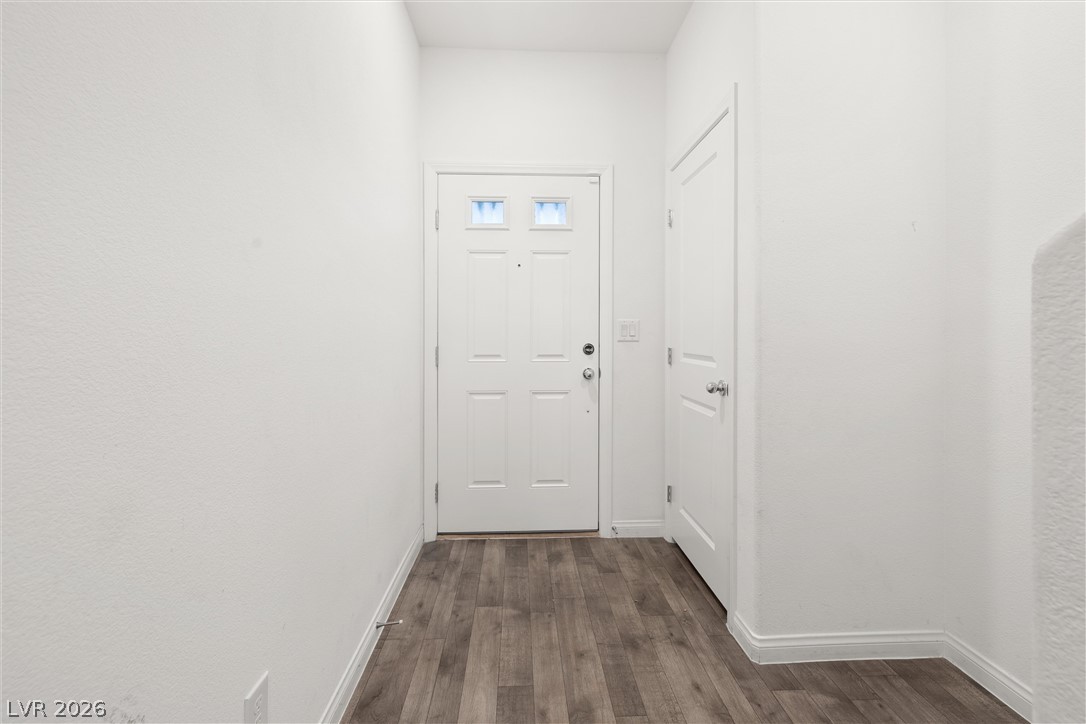 Entry foyer with white doors and gray-brown wood-look flooring.