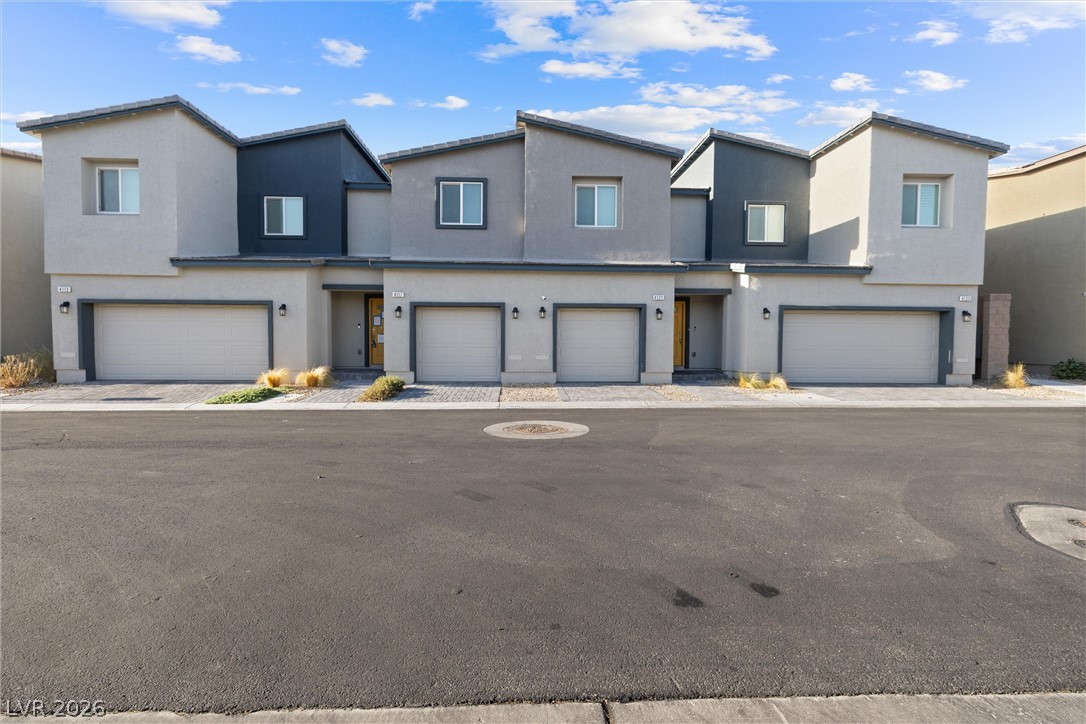Modern gray two-story townhomes with multiple garage doors line a paved street.