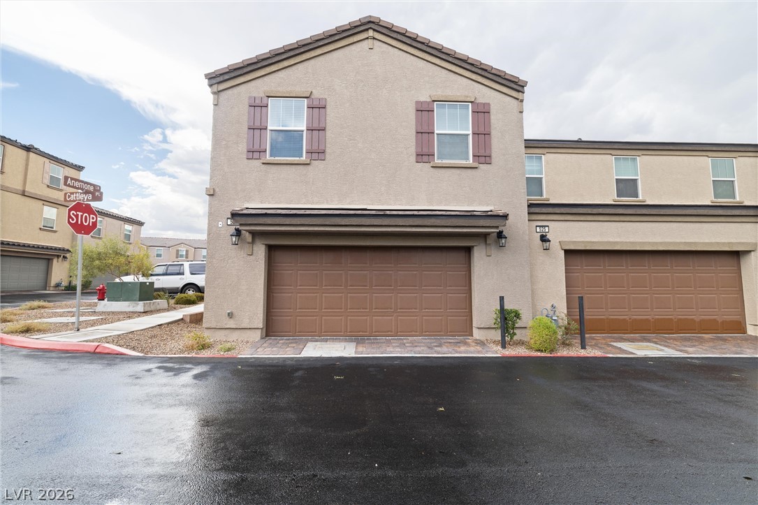 Two-story beige townhouse with mauve shutters and an attached two-car garage.