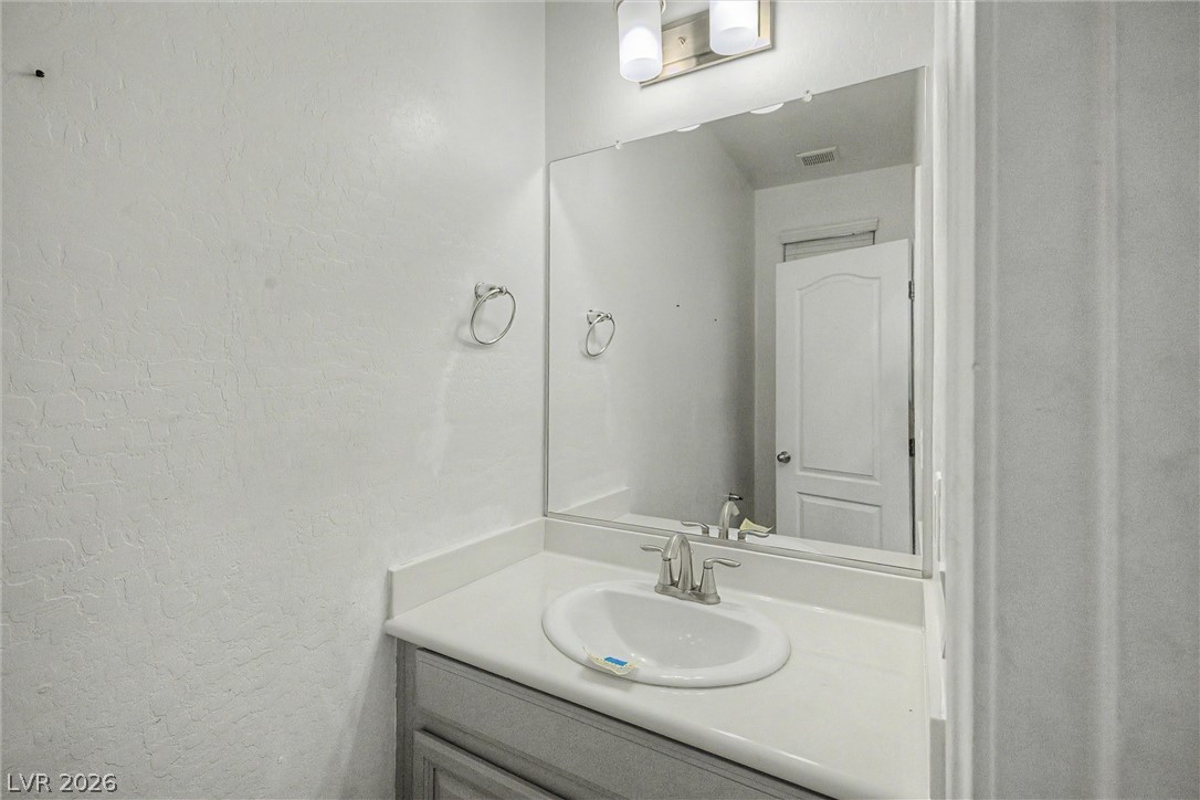 Bathroom vanity with an oval sink, gray cabinet, and large mirror.