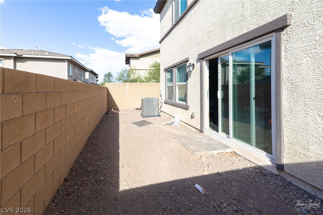 Gravel side yard beside a stucco house, with a sliding glass door and block walls.