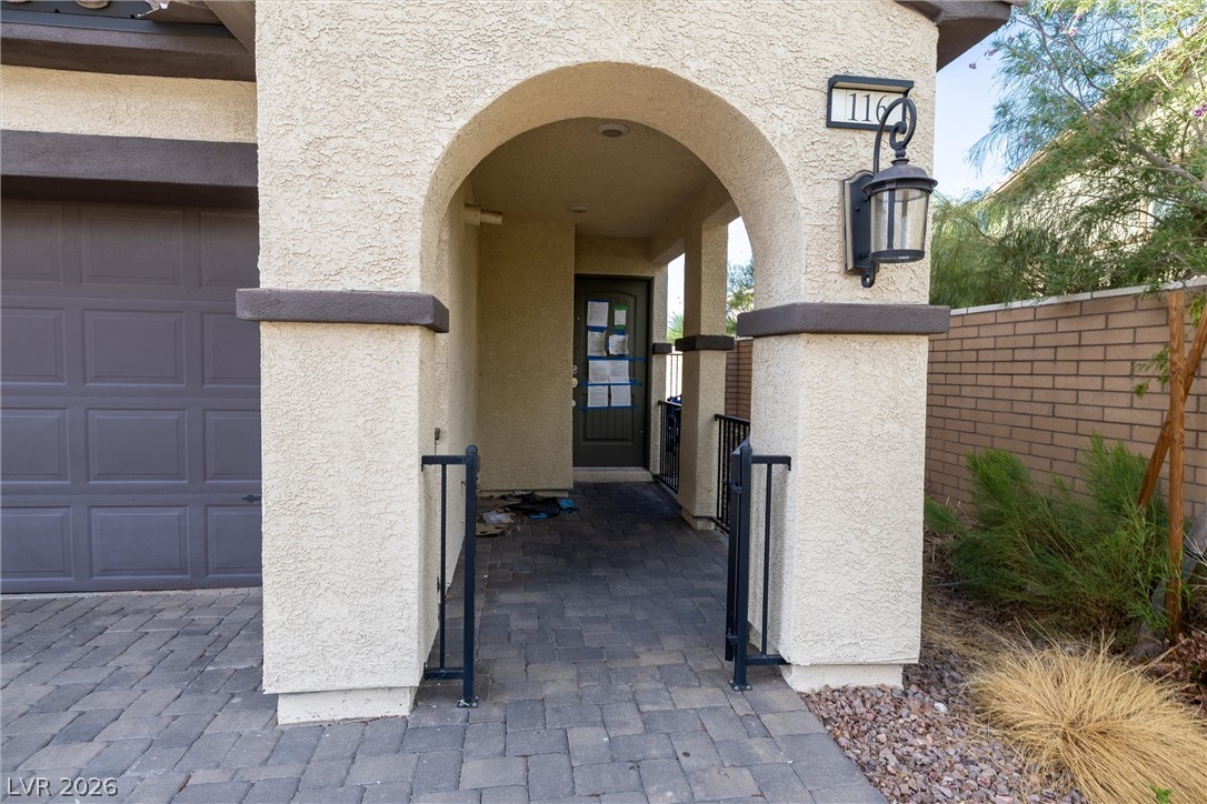 Home entrance with a covered stucco arch, gray paver walkway, and attached garage.