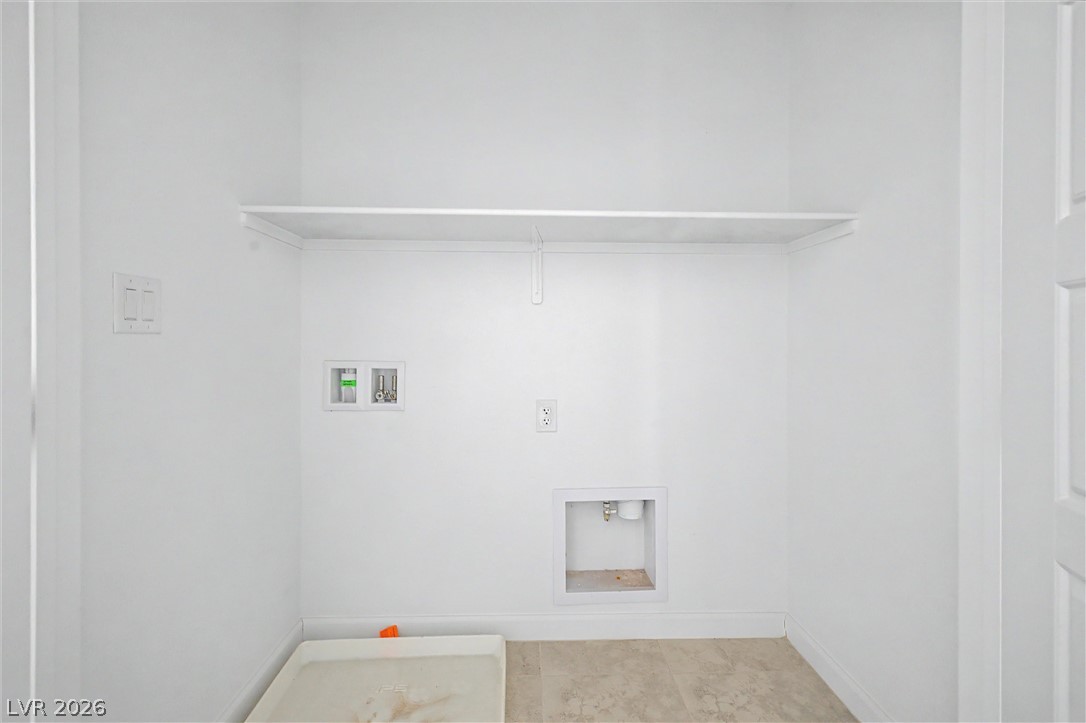 Empty laundry area with washer hookups, an overhead shelf, and a drain pan.