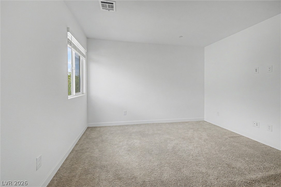 Empty carpeted room with white walls and a window with blinds.