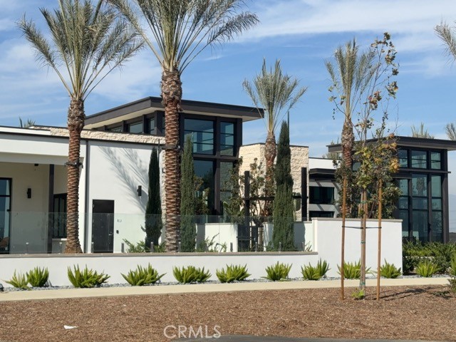 Modern home with large glass windows, stone accents, and palm trees.