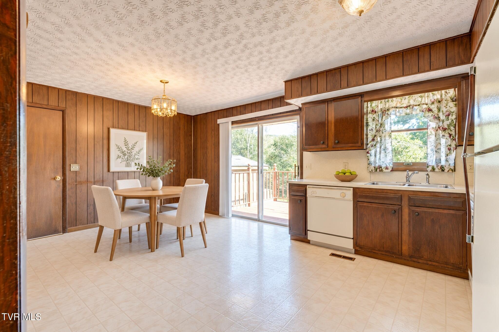 Kitchen and dining area with dark wood cabinets, a dining table, and a sliding door to the deck.